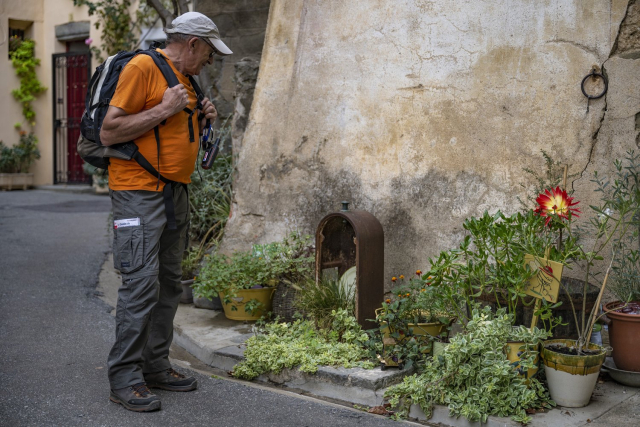 Randonneur regardant massif de fleurs dans les ruelles de Bize-Minervois